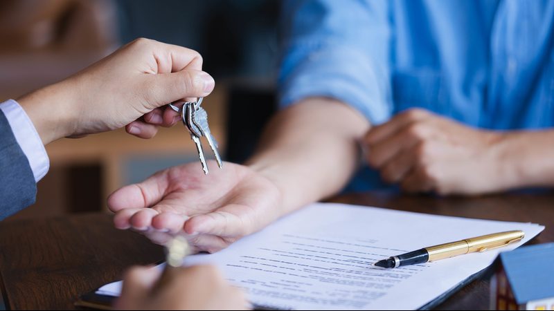 Real-estate agent giving keys to new property owners after signi